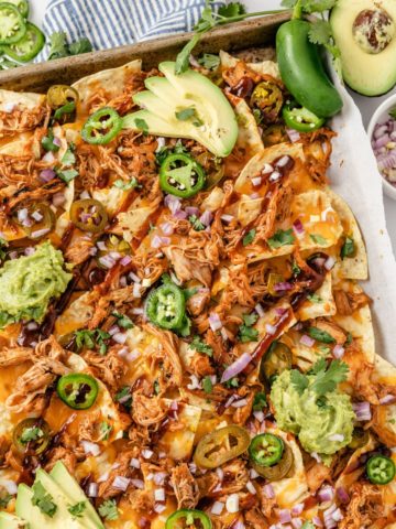 flavorful BBQ Chicken Nachos topped with slices of avocado and red onions