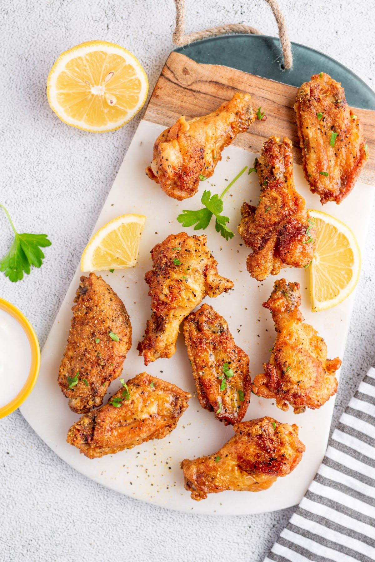 Baked Lemon Pepper Chicken Wings with slices of lemon on a board