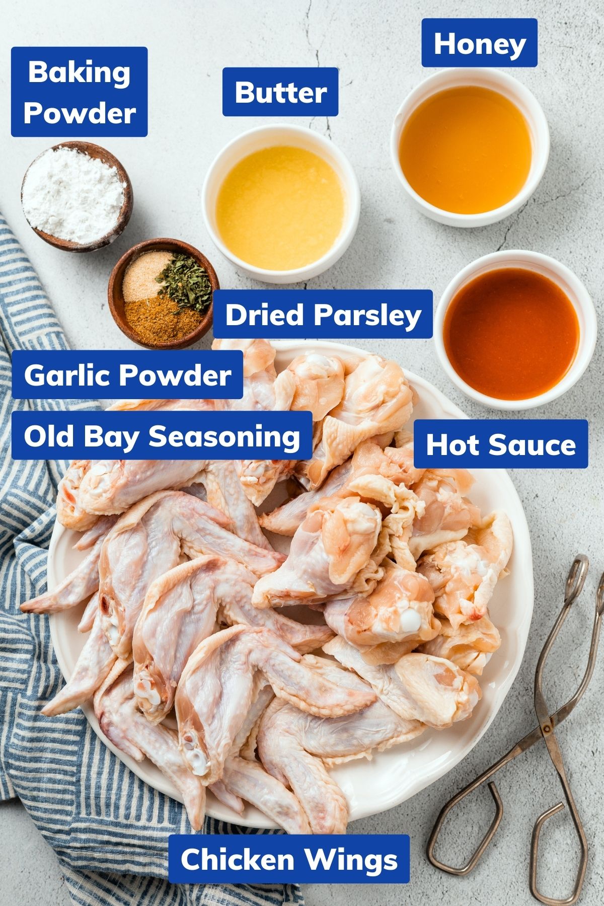 melted butter, baking powder, honey, dried parsley, garlic powder, old bay seasoning, and hot sauce in separate bowls and chicken wings on a large plate