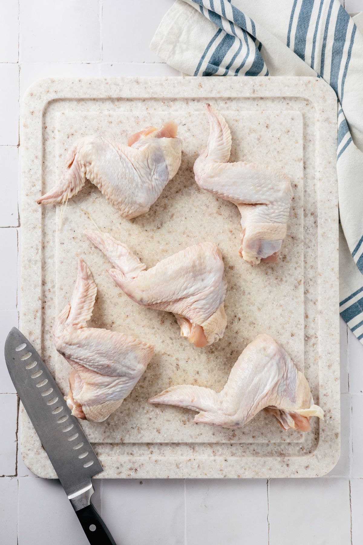 5 pieces of whole chicken wings on a chopping board with a chef's knife