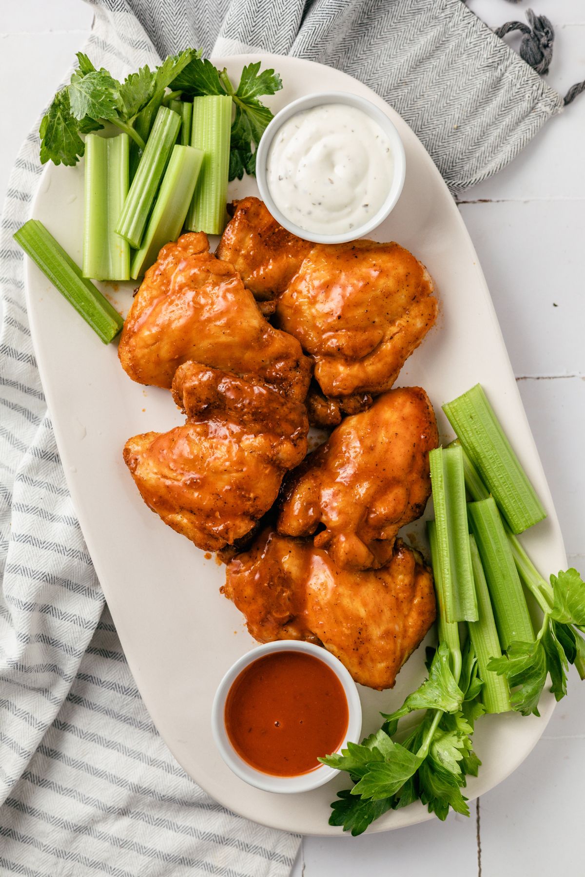 Buffalo Chicken Thighs with ranch dressing and celery sticks on a plate