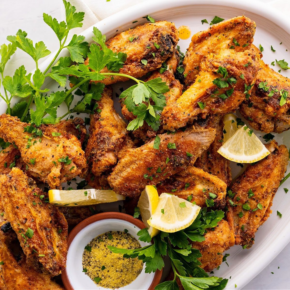 close up photo of crispy Lemon Pepper Air Fryer Wings on a plate with lemon pepper seasoning