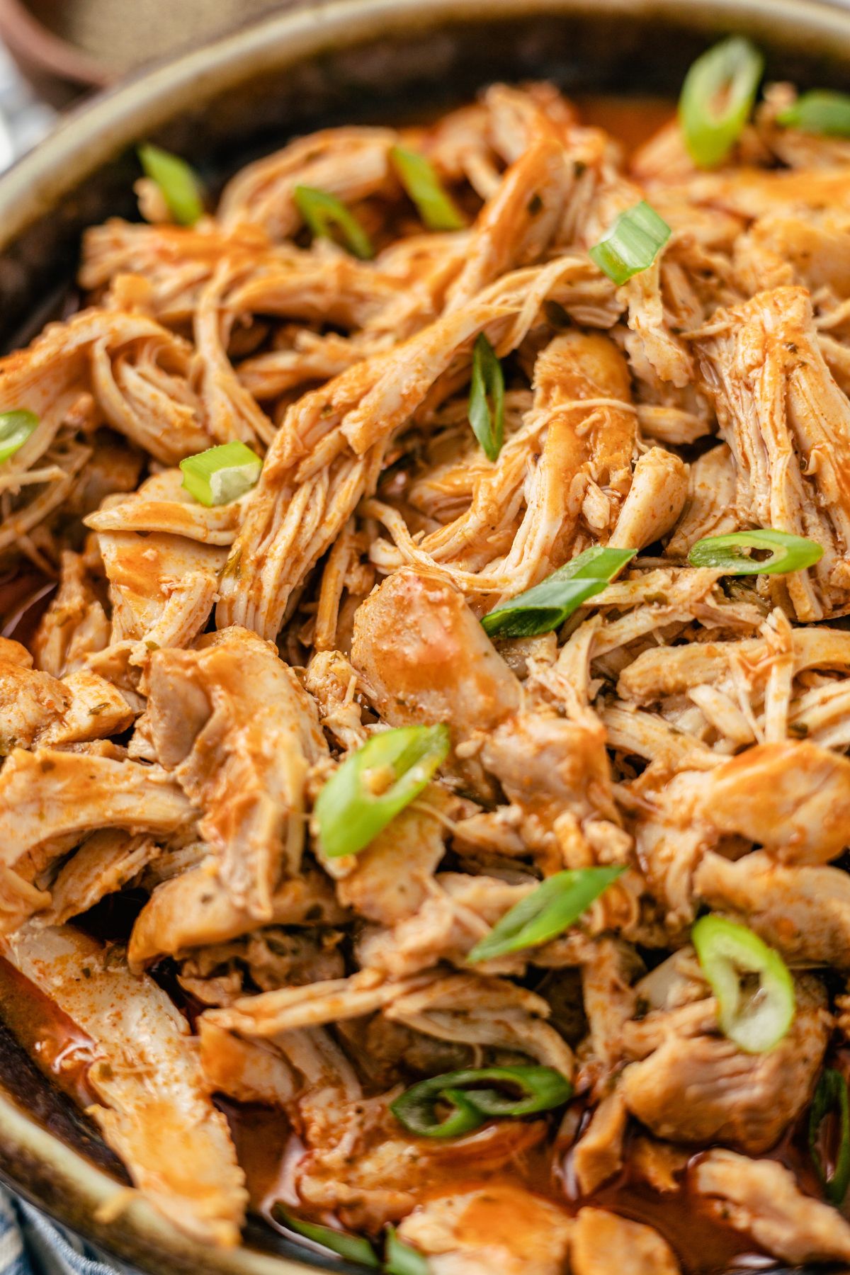 a bowl of pulled chicken with buffalo chicken and green onion