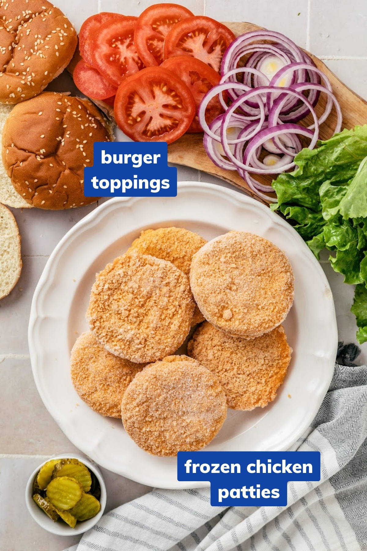 ingredients to make air fryer frozen chicken patties: frozen breaded chicken patties, hamburger buns, red onions, lettuce, pickles, and tomatoes.