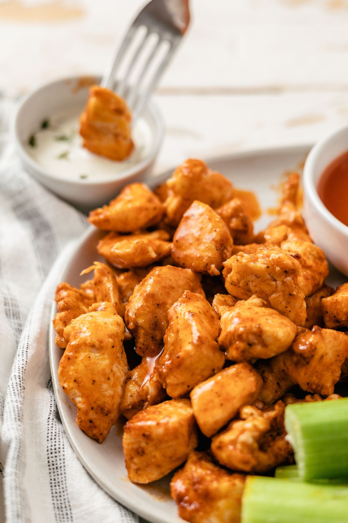 Air Fryer Buffalo Chicken Bites served on a large plate, accompanied by dips and celery sticks on the side