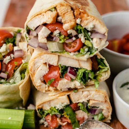 A few mouth-watering pieces of Buffalo Chicken Wrap are elegantly arranged on a wooden board.