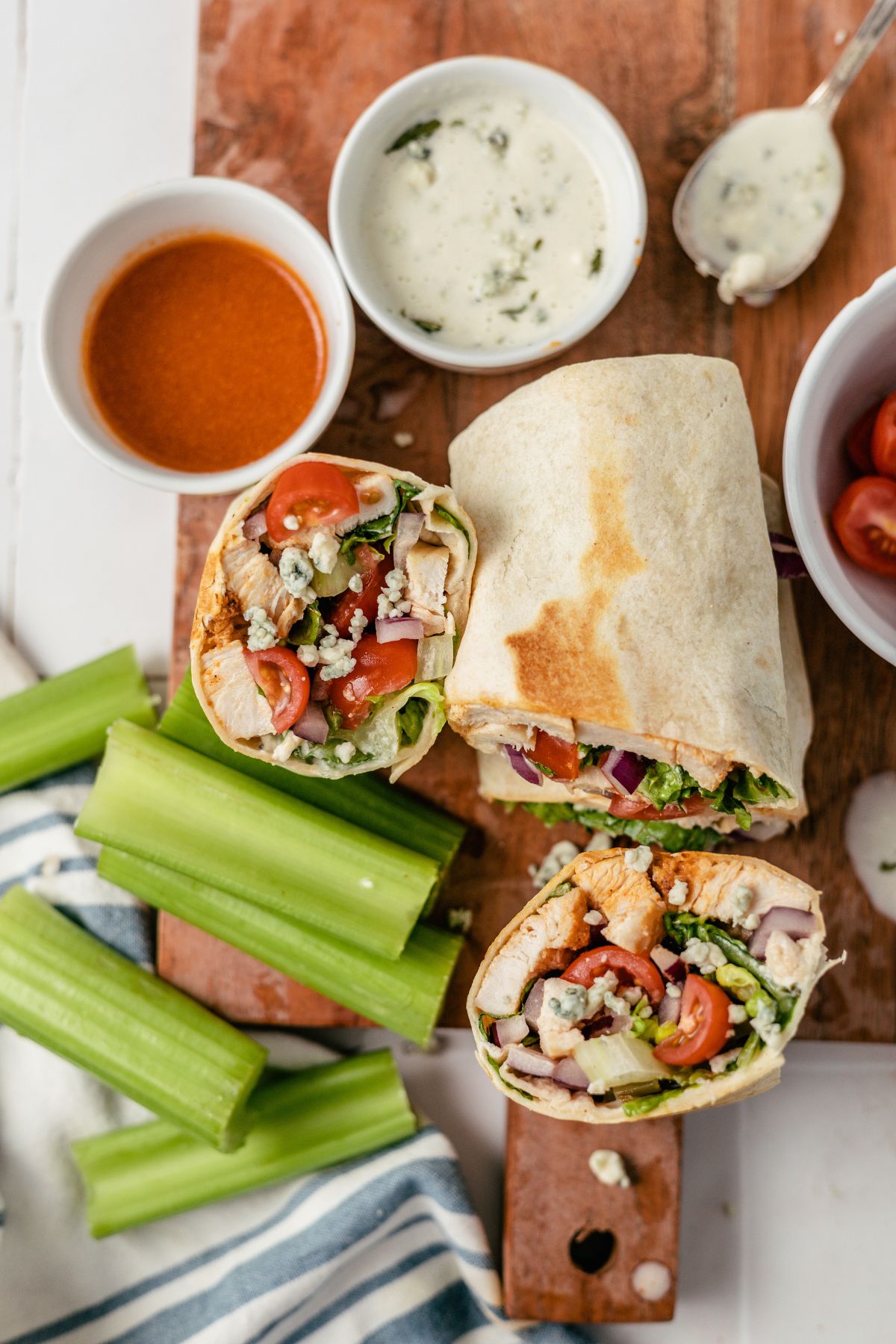 A savory Buffalo Chicken Wrap is complemented by tangy dips and crisp celery on the side