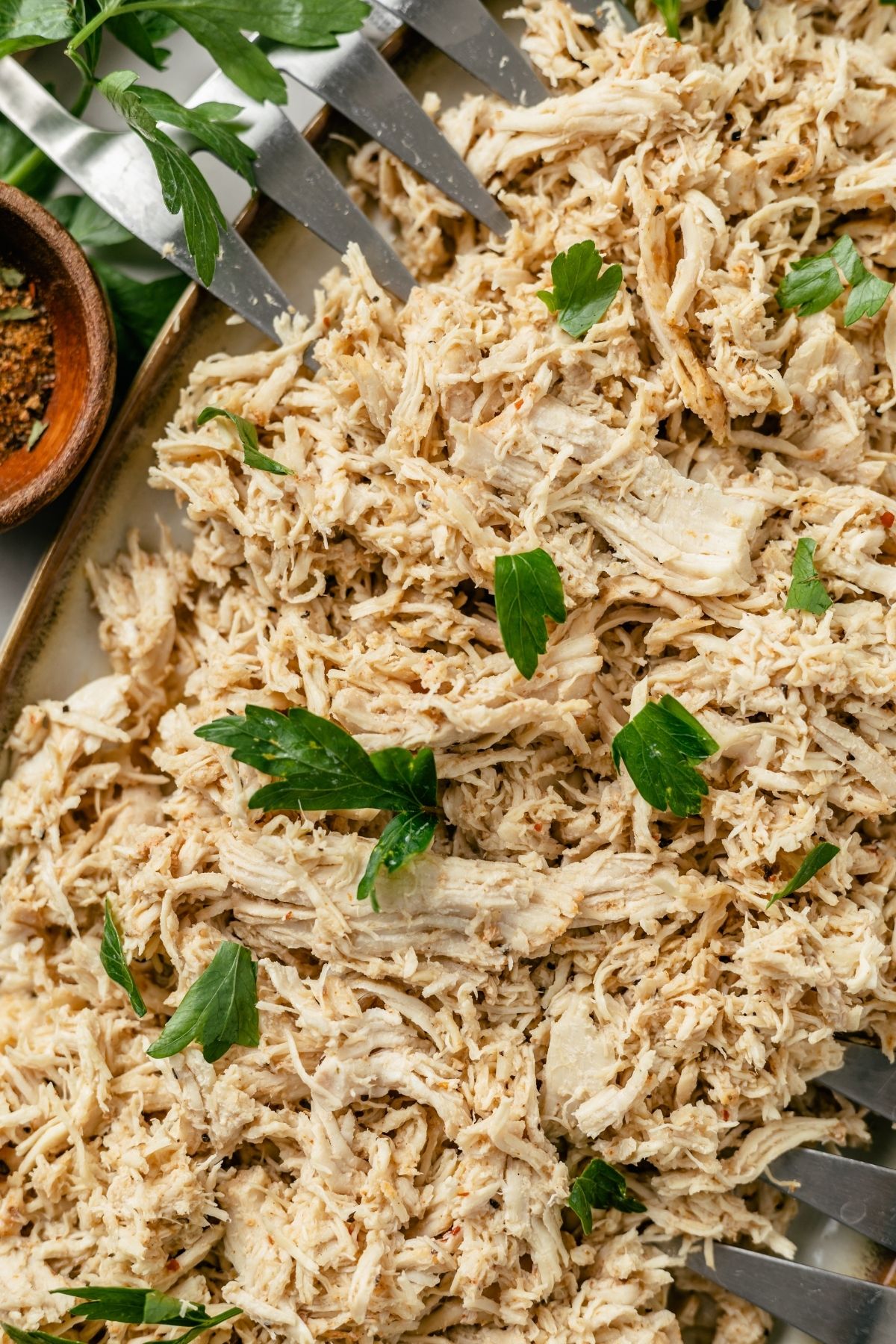 Tender and flavorful shredded chicken cooked in a pressure cooker on a plate with fresh parsley
