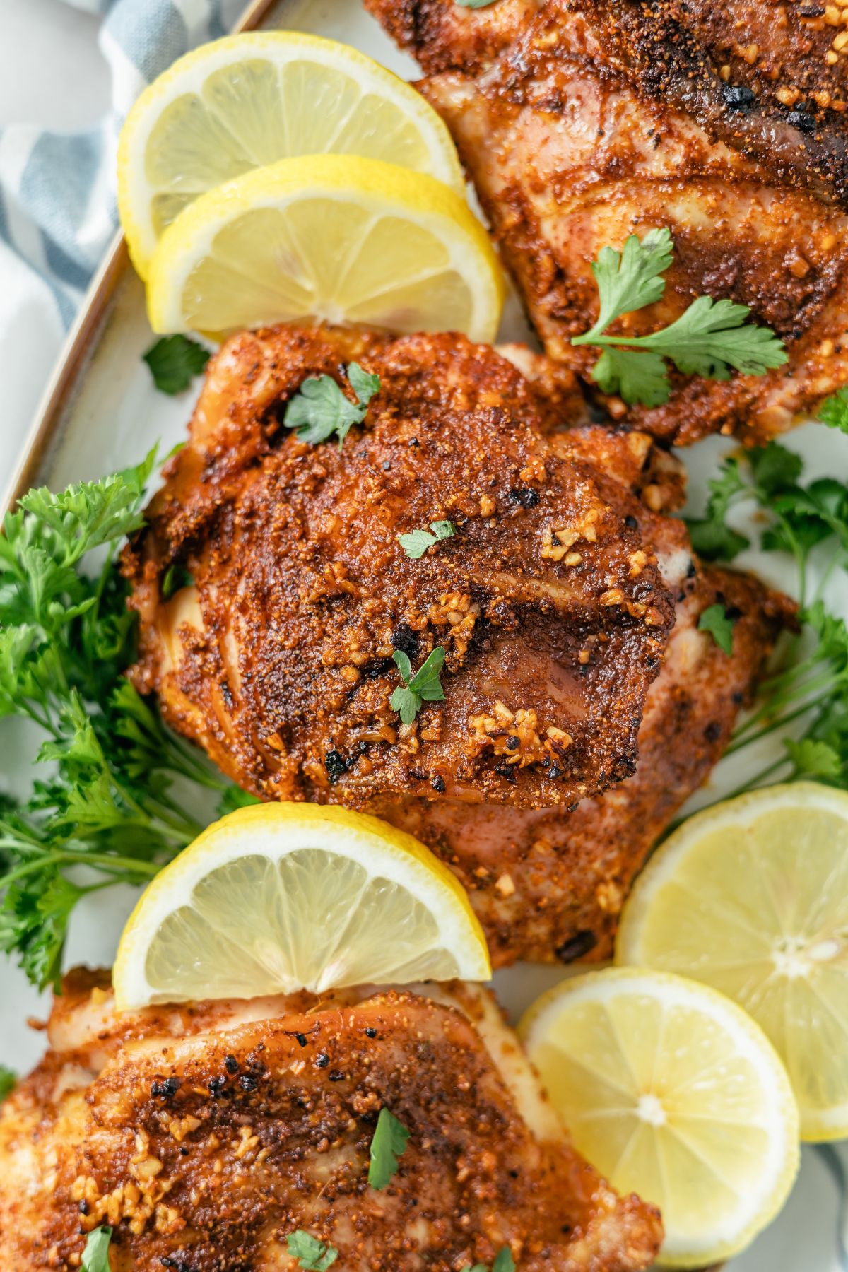 juicy and tasty Baked Cajun Chicken on a plate with slices of lemon and topped with parsley