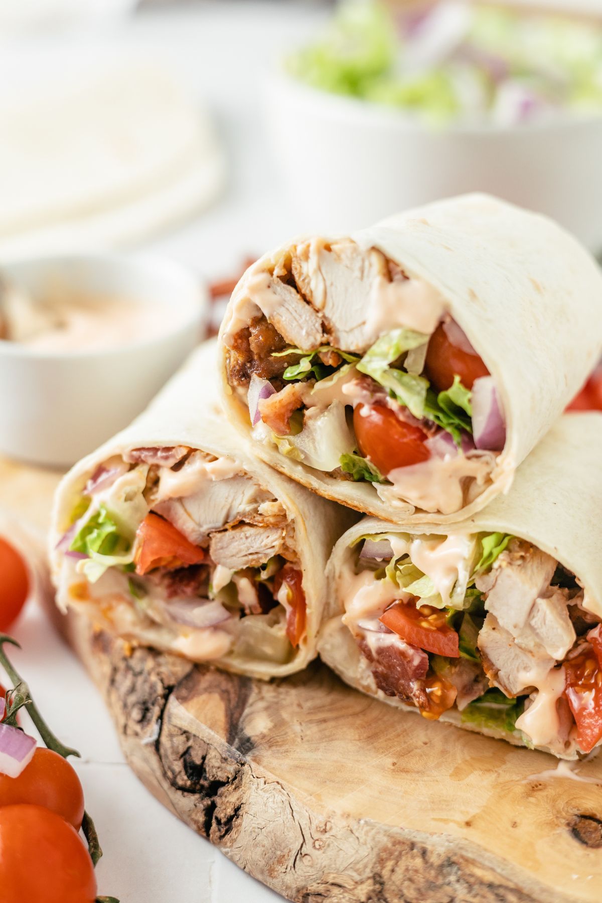 Three tempting Cajun Chicken Wraps on a rustic wooden board.