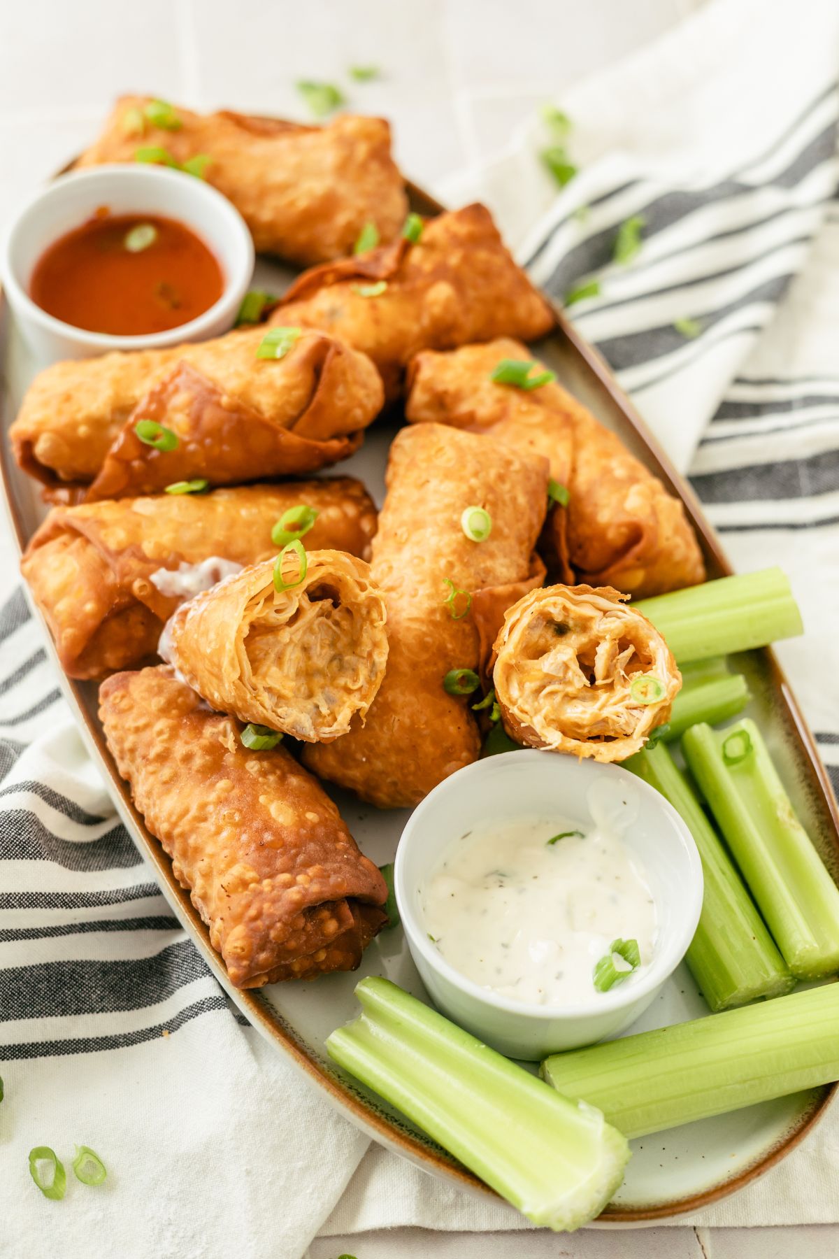 Savory Buffalo Chicken Egg Rolls accompanied by zesty dips and crisp celery sticks for a delicious and satisfying snack