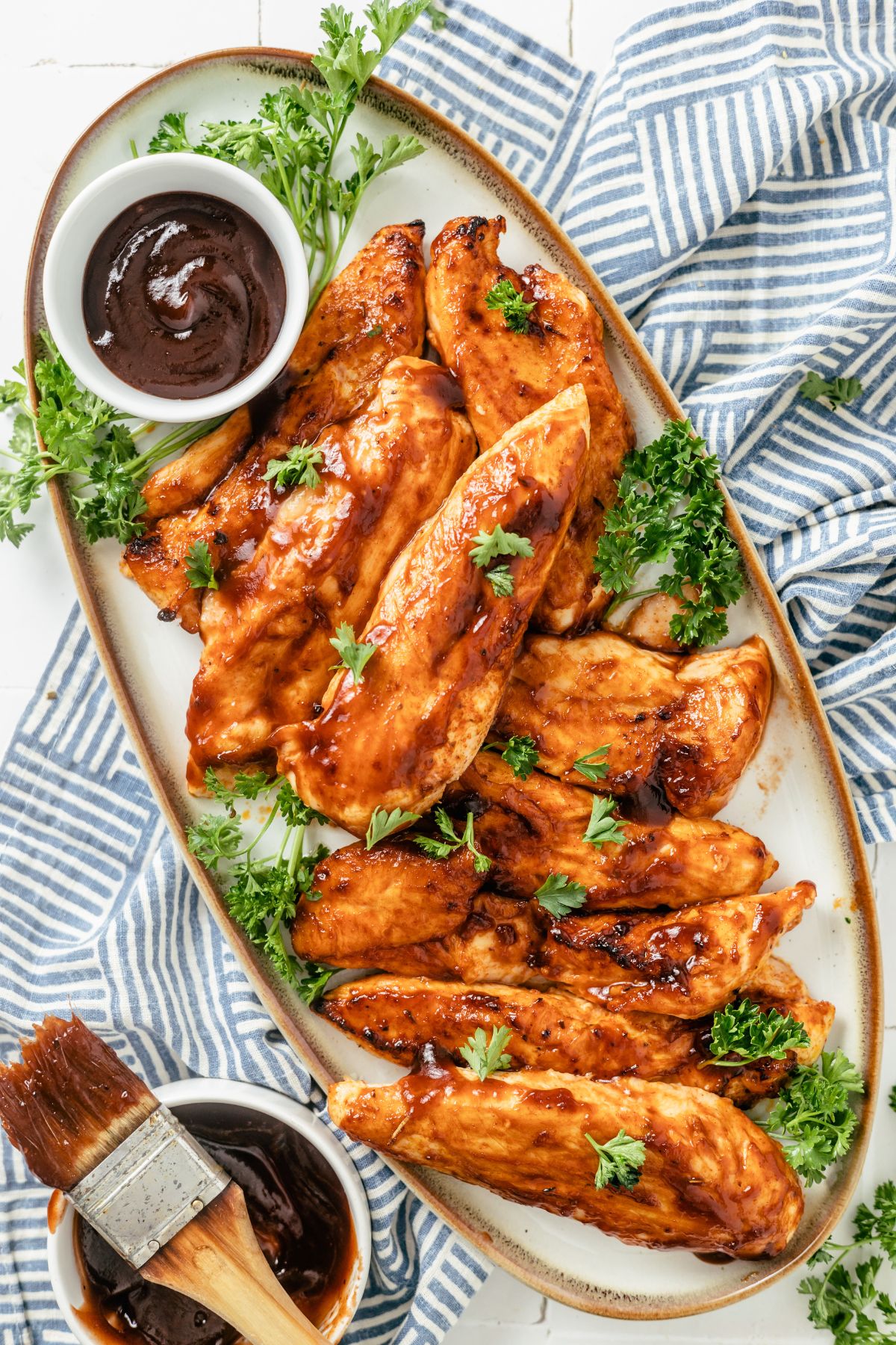 Tender and succulent BBQ chicken tenders artistically arranged on a plate, garnished with fresh parsley for a vibrant touch.