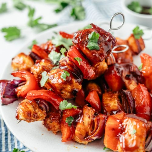 Deliciously grilled chicken kabobs arranged on a plate, showcasing perfectly cooked chunks of seasoned chicken, vibrant bell peppers, and red onion skewered to perfection.