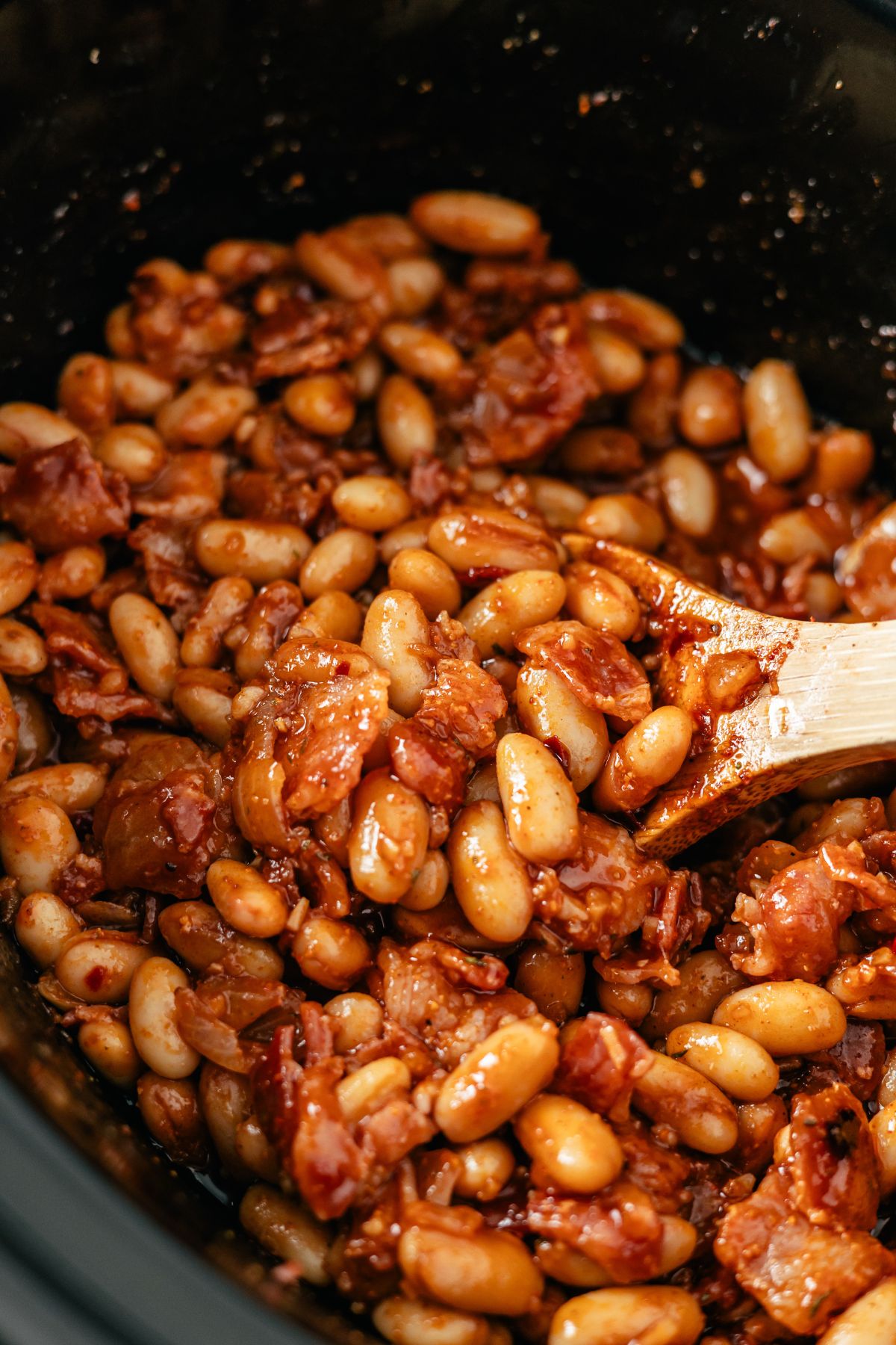 Hearty and flavorful slow cooker baked beans, simmered to perfection, showcasing a rich blend of spices and savory notes in a deliciously thick sauce