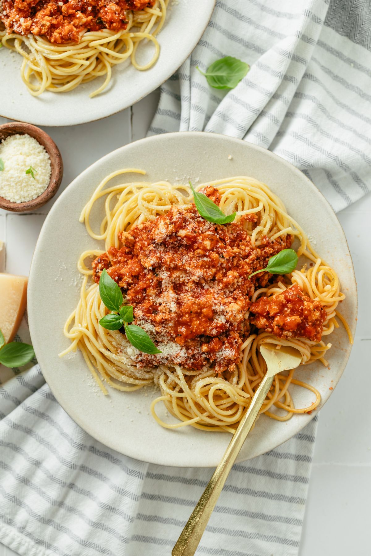 Plate of flavorful ground chicken spaghetti with marinara sauce, fresh basil and grated parmesan cheese. 