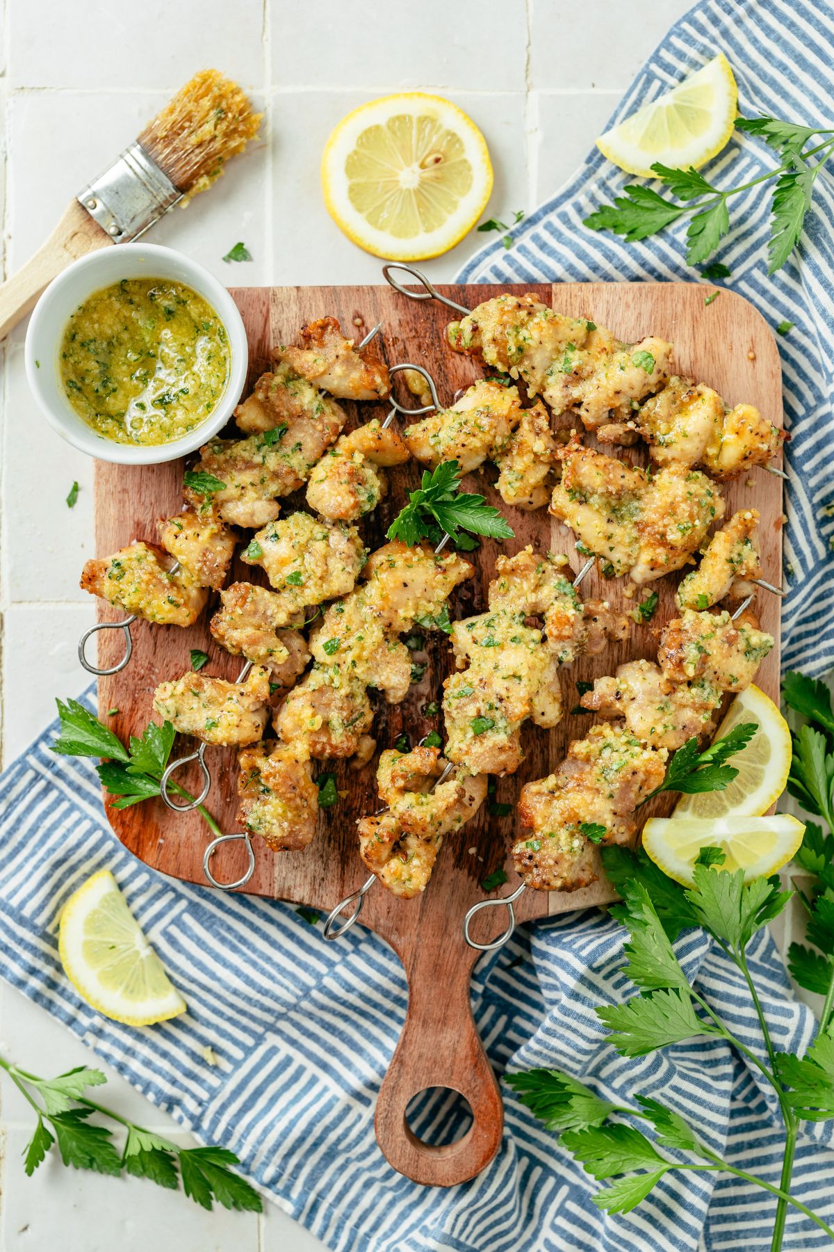 Garlic Parmesan Chicken Skewers arranged on a rustic wooden board, garnished with fresh herbs and lemon wedges