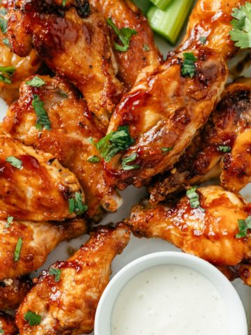 Golden-brown air-fried frozen chicken wings arranged on a platter, crispy on the outside and juicy on the inside, garnished with a sprinkle of fresh herbs.