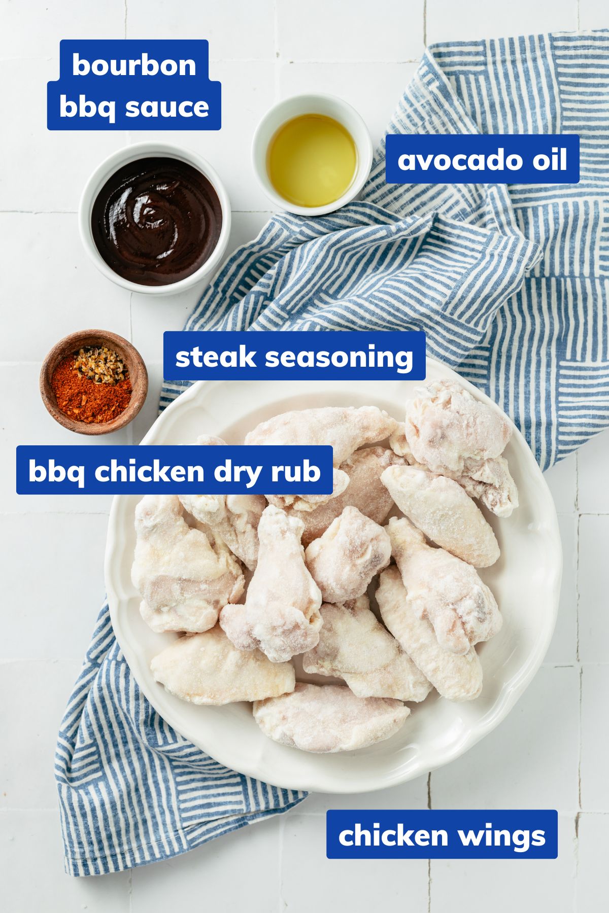 Ingredients for air-fried frozen chicken wings arranged in separate bowls: individually frozen chicken wings, steak seasoning, BBQ chicken dry rub, avocado oil, and bourbon BBQ sauce.