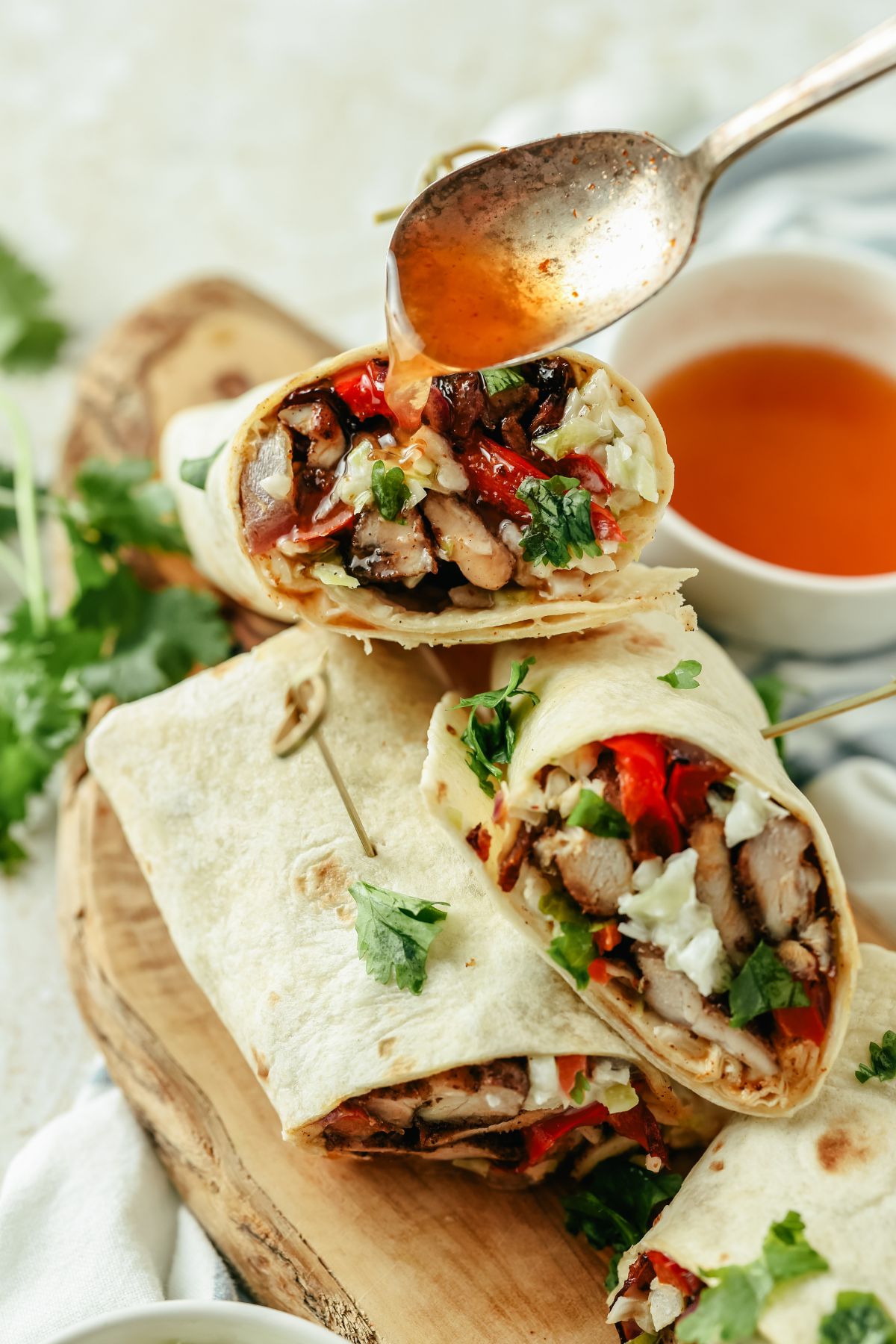 Jerk chicken wrap topped with extra sauce, filled with chicken, fresh veggies, and wrapped in a soft tortilla, ready to enjoy.